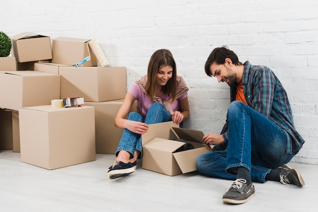 Young couple opening the cardboard boxes in their new house