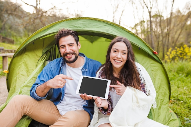 Free photo young couple pointing at tablet in nature