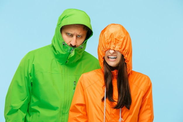 young couple posing at studio in autumn jackets isolated on blue