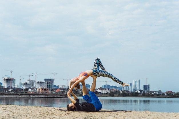 Free Photo young couple practicing yoga on city background