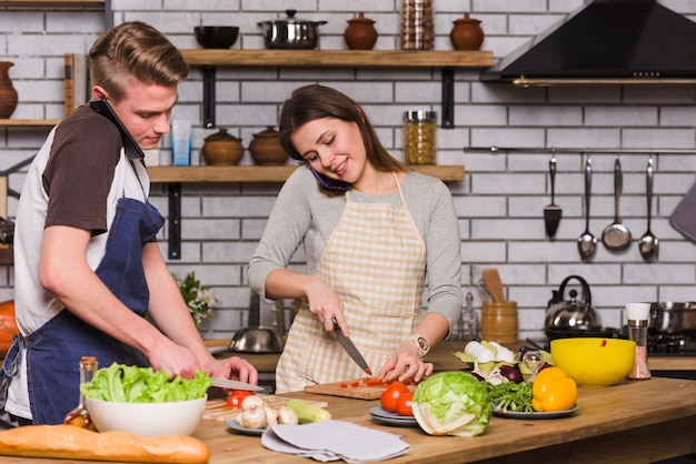 Free photo young couple preparing salad during smartphone conversation