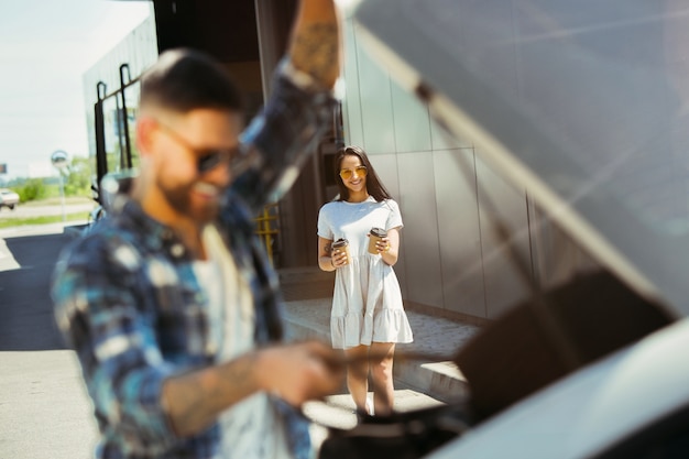 Free photo young couple preparing for vacation trip on the car in sunny day