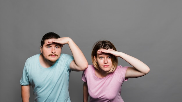 Young couple shielding eyes with her hands on grey background