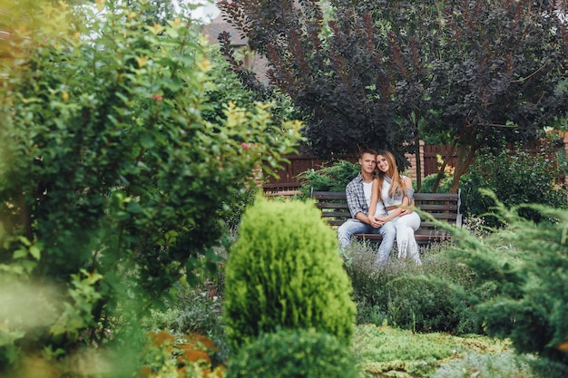 Free photo young couple sitting on a bench at the park and looking at front