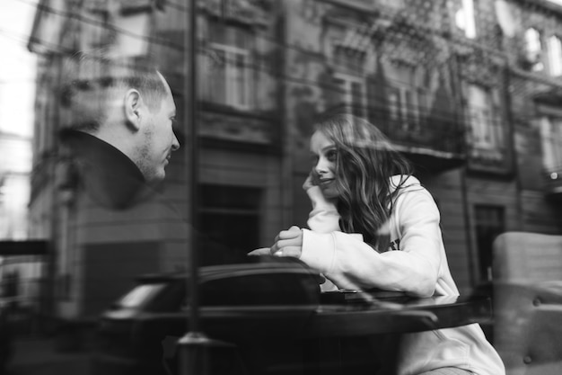 Young couple sitting in a cafe behind the window