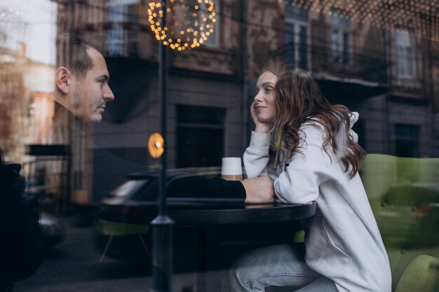 Free Photo young couple sitting in a cafe behind the window