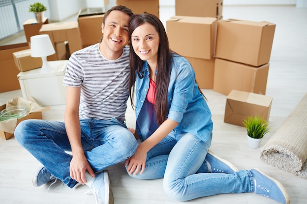 Young couple sitting on floor with moving boxes