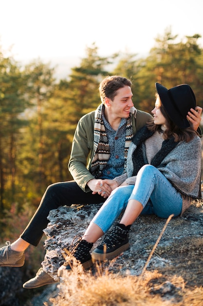 Free Photo young couple sitting on a rock outdoors