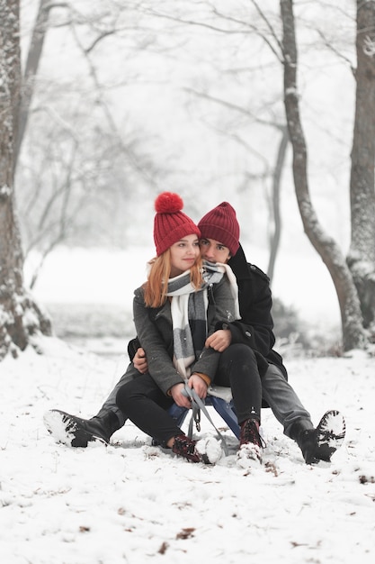 Free photo young couple sitting on sleigh in winter daylight