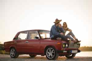 Free photo young couple sitting on a vintage car