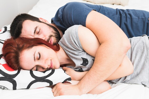 Young couple sleeping together on bed