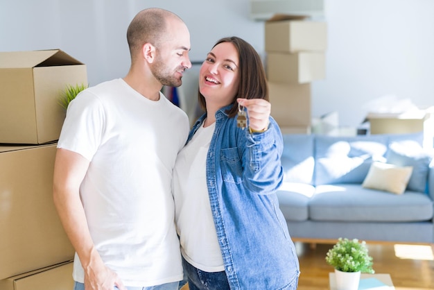 Free photo young couple smiling very happy showing keys of new home, moving and buying new apartmet concept