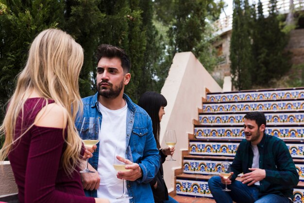 Young couple standing near staircase with glass of wine