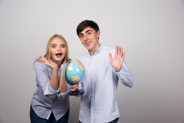 Young couple standing and posing with an Earth globe