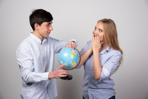 Young couple standing and posing with an Earth globe