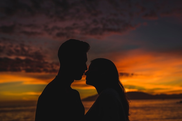 Young couple standing on sea shore in night 