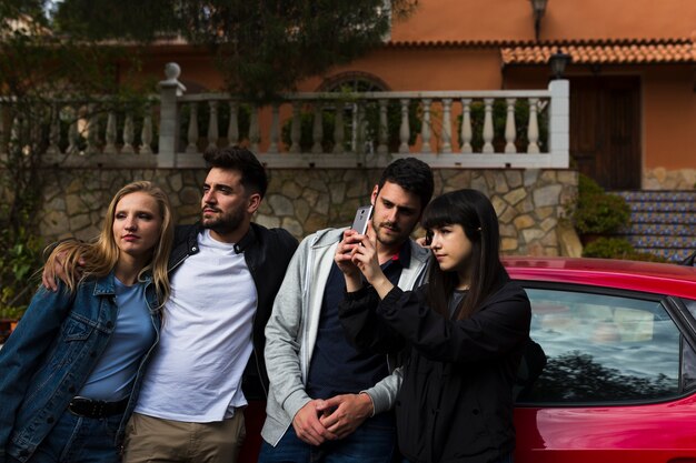 Young couple taking selfie in front of car