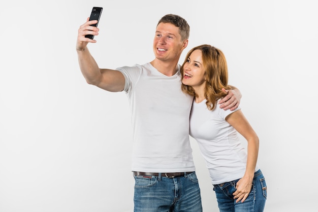 Young couple taking selfie on mobile phone isolated on white background