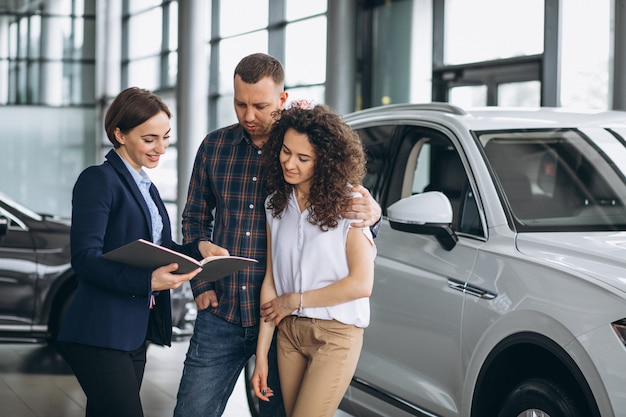 Young couple talking to a sales person in a car showroom