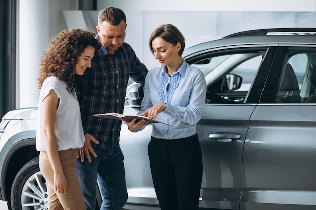 Young couple talking to a sales person in a car showroom