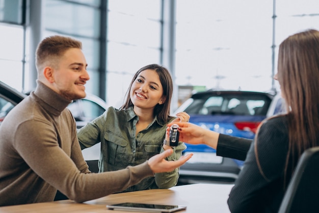 Young couple talking to a sales person in a car showroom