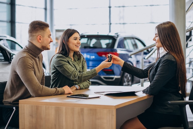 Young couple talking to a sales person in a car showroom