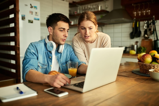 Young couple talking while using laptop at home