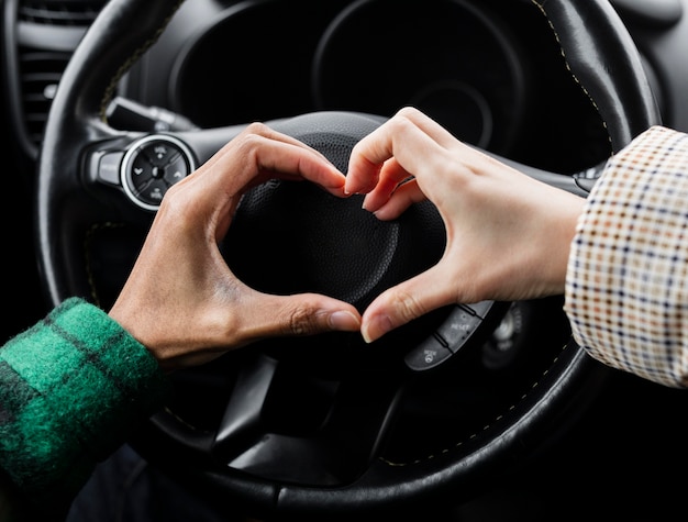 Young couple traveling with car close up doing heart shape