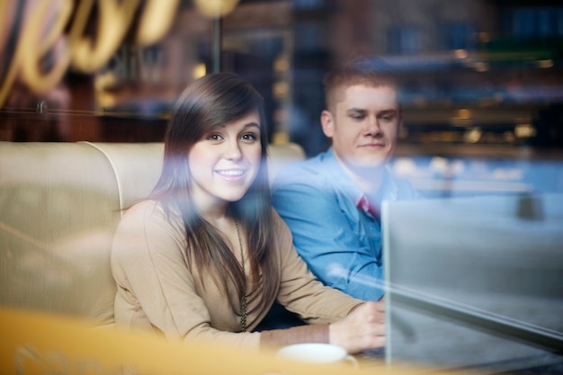 Free photo young couple using laptop in coffee shop