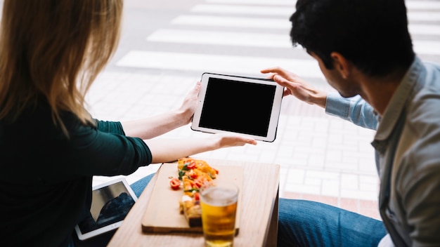 Free photo young couple using tablet in cafe