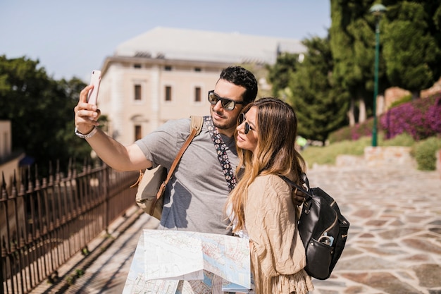 Free photo young couple on vacation taking self portrait with cell phone