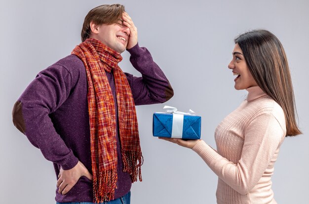 Young couple on valentines day smiling girl giving gift box to crying guy isolated on white background