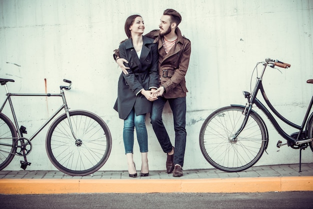 Free photo young couple with a bicycle opposite city