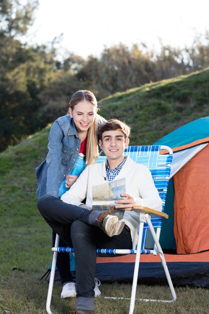 Young couple with a map next to the tent