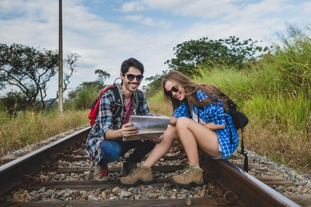 Young couple with map on train tracks