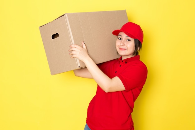 young courier in red polo red cap holding package smiling on yellow