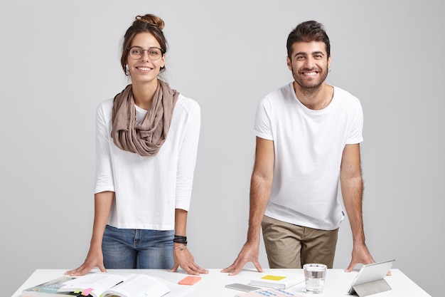 Free photo young coworkers standing near desk