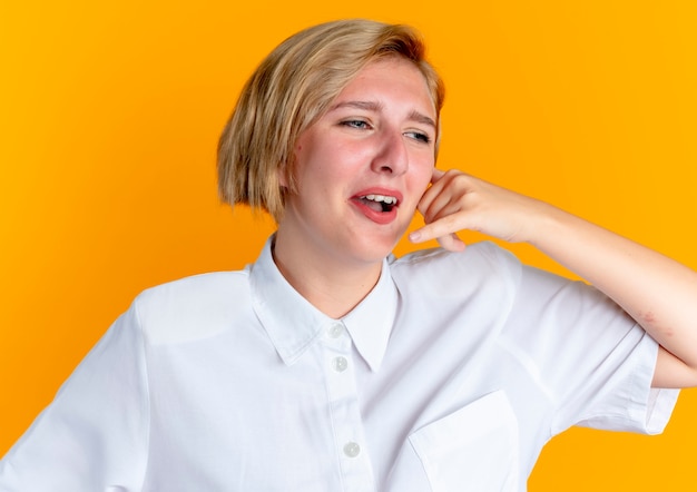 Free Photo young crying blonde russian girl gestures call sign isolated on orange background with copy space