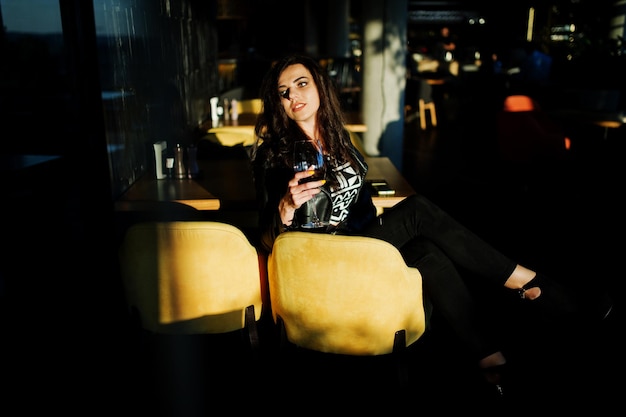 Free photo young curly woman enjoying her wine in a bar