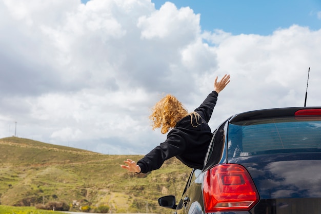 Free photo young curly woman leaning out of car window