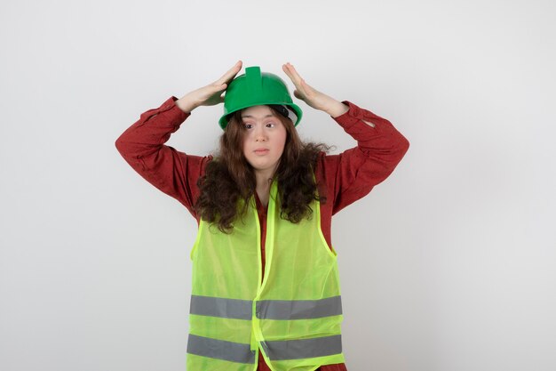 young cute girl standing in vest and wearing a crash helmet .