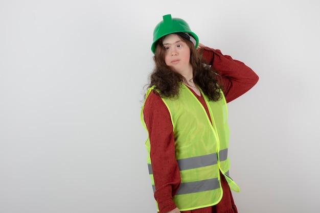 Free photo young cute girl with down syndrome standing in vest and holding crash helmets .