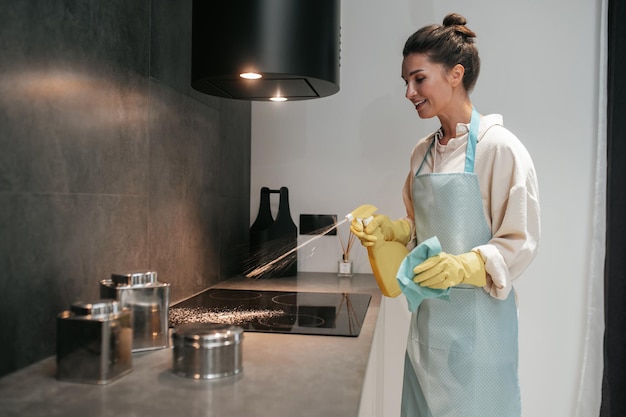 Free photo young dark-haired woman disinfecting the surfaces in the kitchen