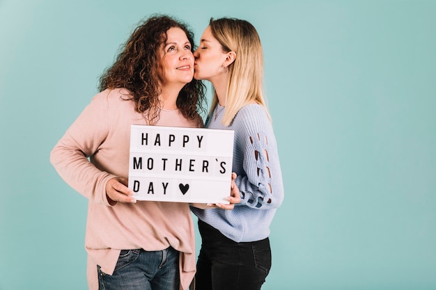 Free photo young daughter kissing mom on mother's day