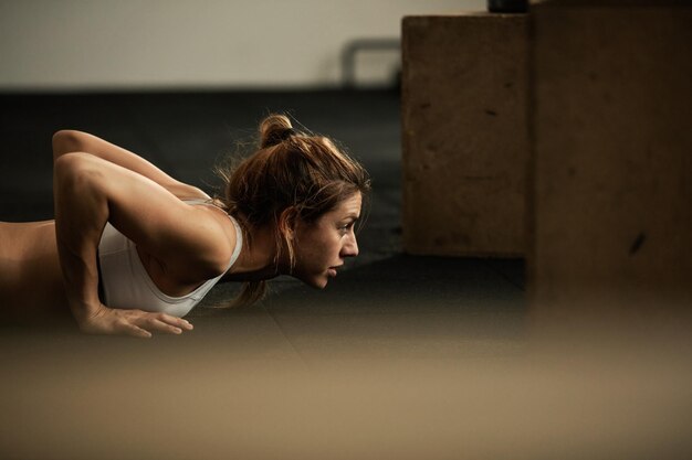 Young dedicated sportswoman exercising pushups during sports training in health club Copy space