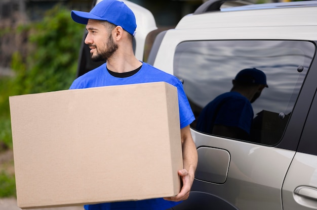 Free photo young delivery man carrying cardboard box