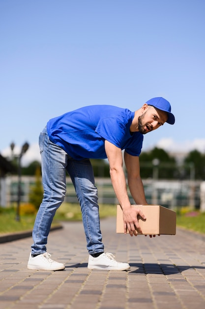 Free photo young delivery man carrying cardboard box