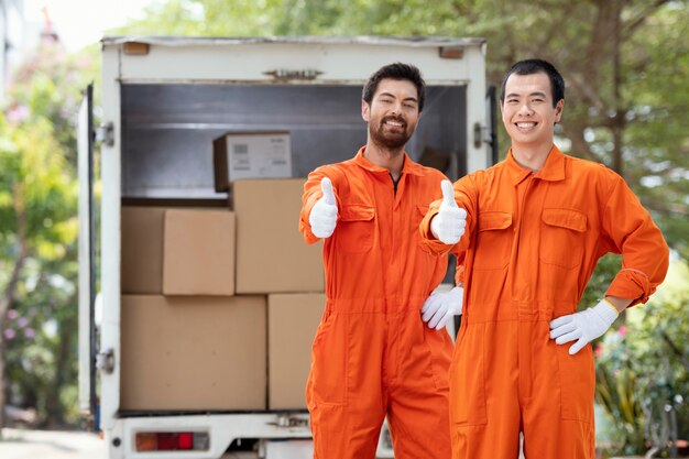 Young delivery men showing ok sign near delivery car