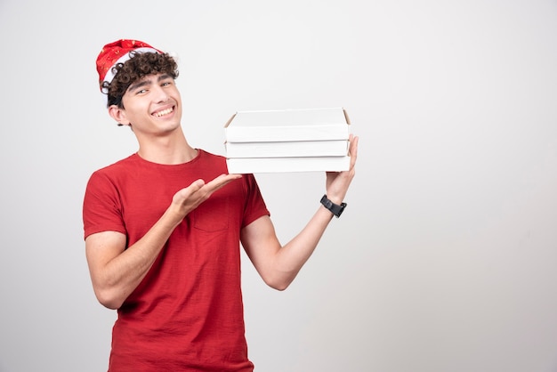 Free photo young deliveryman showing off pizza boxes.