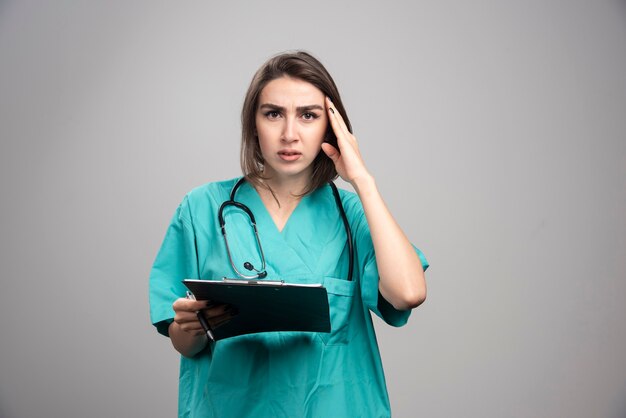 Young doctor having headache on gray background. High quality photo